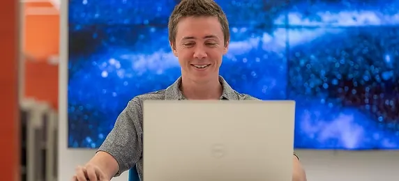 Member working on a laptop in front of the galaxy wall at World Park