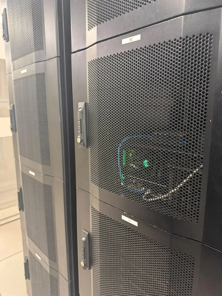 Close-up of a perforated server cabinet door with active equipment indicator lights at MarQi Cloud colocation in Alpharetta