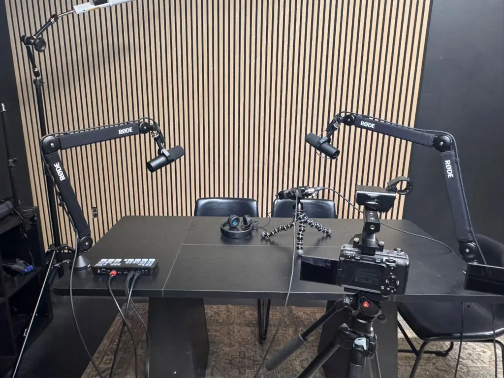 Podcast and video studio at World Park in Alpharetta with broadcast microphones, a camera on a tripod and an acoustic wood-slat wall