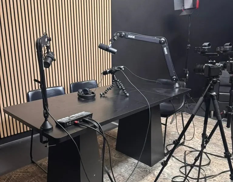 Podcast studio desk with broadcast microphones and an acoustic wood-slat wall at World Park in Alpharetta, Georgia