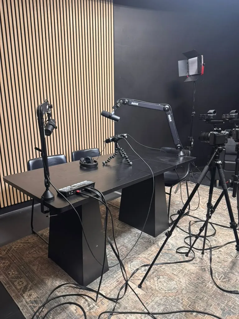 Podcast studio desk with broadcast microphones and an acoustic wood-slat wall at World Park in Alpharetta, Georgia